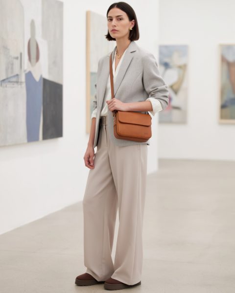 Junge Frau in Blazer und weiter Hose in einer Galerie